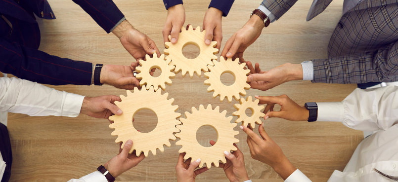 Mensen maken culturen en culturen maken mensen. Mensen die samen tandwielen vasthouden als metafoor voor teamcultuur en samenwerking.