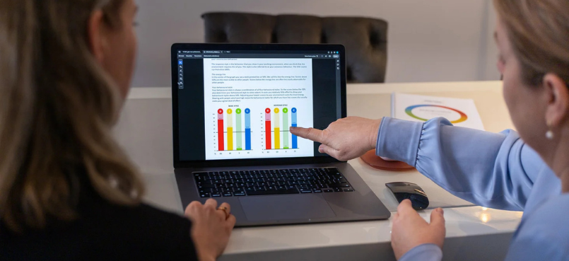 Coach bespreekt DISC-gedragsprofiel op laptop met grafieken, gericht op inzicht in communicatie en teamdynamiek.